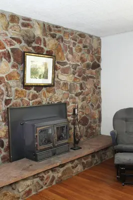 a fireplace in a room with a stone wall at Kern Riverview Inn in Kernville