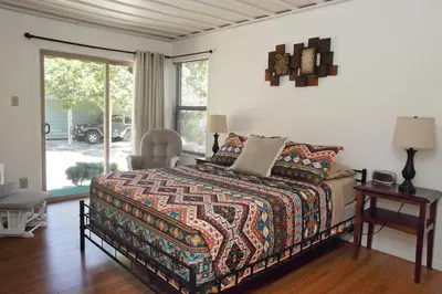 a bedroom with a bed and a chair and a window at Kern Riverview Inn in Kernville