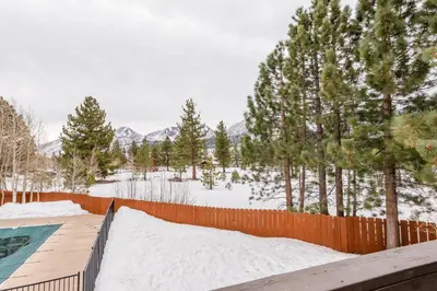a fence with snow and trees and a pool at Chateau Blanc 11 in Mammoth Lakes