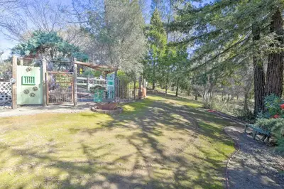 a yard with a gate and a bench in a park at Wine Lovers Garden Oasis in Sutter Creek! in Sutter Creek