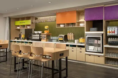 a kitchen with a counter with chairs and a refrigerator at Home2 Suites By Hilton Clovis Fresno Airport in Clovis