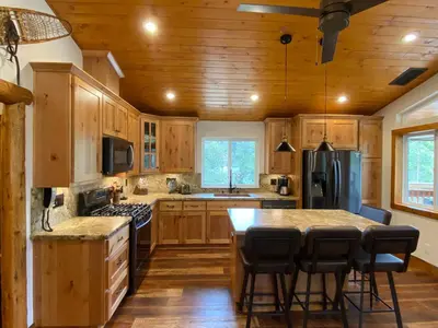 a kitchen with wooden cabinets and a island with bar stools at Pioneer in Oakhurst