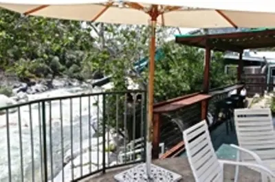 a patio with an umbrella and two chairs and a table at The Gateway Restaurant & Lodge in Three Rivers