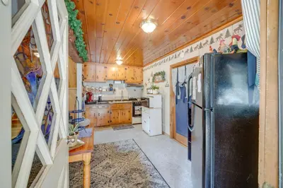 a kitchen with a black refrigerator and wooden cabinets at Mountain Tops Ponderosa Getaway Near Dome Rock! in Ponderosa