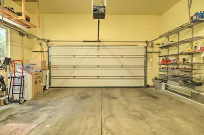a garage with a white garage door and shelves at Near Hiking Home with Deck in Twain Harte! in Twain Harte