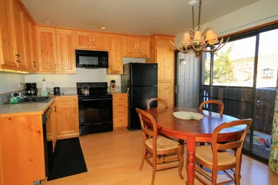 a kitchen with a wooden table and a black refrigerator at Sierra Park Villas 23 in Mammoth Lakes