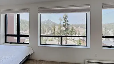 a bedroom with windows with a view of a mountain at Comfortable 2 BR Loft Slope View Condo! in Mammoth Lakes