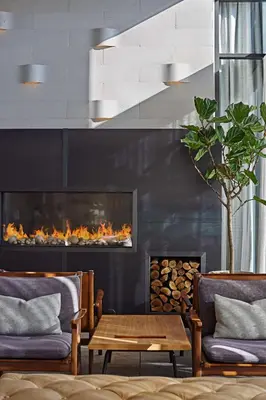 a living room with two chairs and a fireplace at Tapestry By Hilton The Fort Sutter Hotel Sacramento, Ca in Sacramento