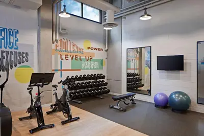 a fitness room with exercise equipment and a television at Tapestry By Hilton The Fort Sutter Hotel Sacramento, Ca in Sacramento