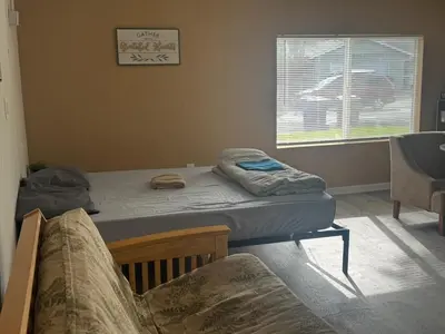 a bedroom with two beds and a chair and a window at WHOLE Family - Rosemont in Sacramento