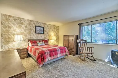 a bedroom with a bed and a chair and a window at Home with Serene Deck in Twain Harte! in Twain Harte