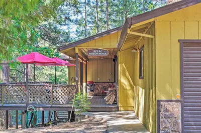a yellow house with a porch and a pink umbrella at Home with Serene Deck in Twain Harte! in Twain Harte