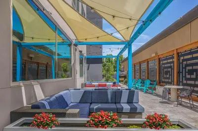 a patio with blue couches and flowers in front of a building at Tru By Hilton Lathrop in Lathrop