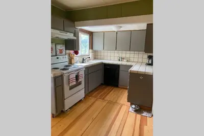 a kitchen with white appliances and a wooden floor at Vans Yosemite Garden Cottage in Groveland
