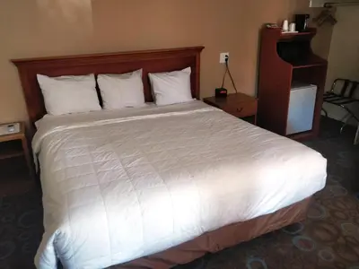 a bedroom with a large bed with white sheets and pillows at Ventura Grand Inn in Mammoth Lakes