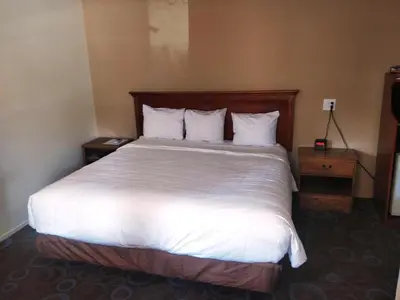 a bedroom with a large bed with white sheets and pillows at Ventura Grand Inn in Mammoth Lakes