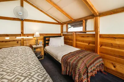 a bedroom with a bed in a room with wooden walls at SoCal Camping in Kernville