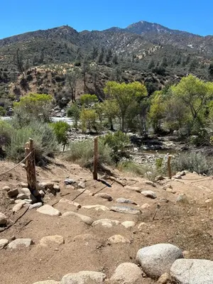a rocky field with trees and mountains in the background at SoCal Camping in Kernville
