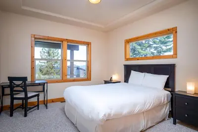 a bedroom with a bed and a desk and two windows at Tahoe Donner Pinnacle Loop Mountain Retreat home in Truckee