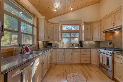 a kitchen with wooden cabinets and a wooden floor at Tahoe Donner Pinnacle Loop Mountain Retreat home in Truckee
