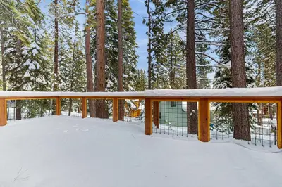 a deck covered in snow with trees in the background at Piney Retreat in Carnelian Bay