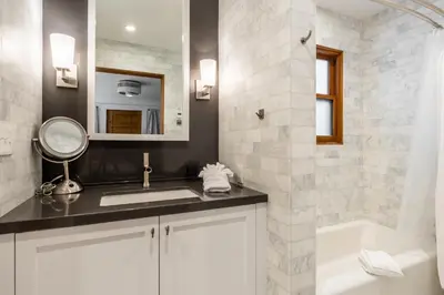 a bathroom with a sink and a mirror and a tub at Cedar Crest - Osprey Cottage 3 in Homewood