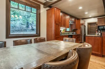 a kitchen with a large wooden table and leather chairs at Cedar Crest - Owl Cottage 9 in Homewood
