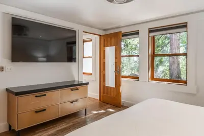 a bedroom with a bed and a dresser and windows at Cedar Crest - Sparrow Cottage 1 in Homewood