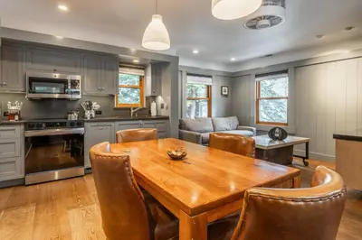 a kitchen and living room with a wooden table and chairs at Cedar Crest-Stellars Jay Cottage 4 in Homewood