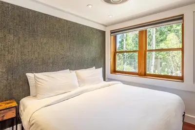 a bedroom with a white bed and a window at Cedar Crest - Woodpecker Cottage 7 in Homewood