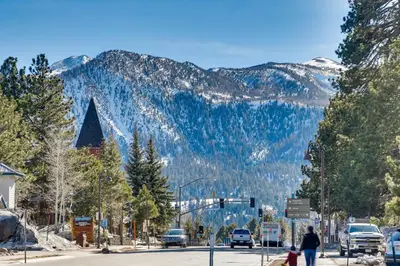 a man and a child crossing a street in front of a mountain at Resort Condo with Hot Tub and Pool, Near Ski Lift in Mammoth Lakes