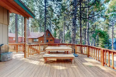 a wooden deck with a picnic table and a cabin at Williams Cabin in Shaver Lake
