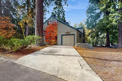 a house with a garage in the woods at Whispering Pines in Shaver Lake