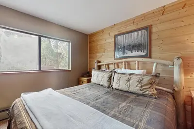 a bedroom with a wooden accent wall and a bed at Whispering Pines in Shaver Lake