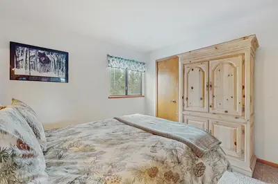 a bedroom with a bed and a wooden cabinet at Whispering Pines in Shaver Lake