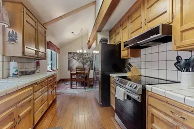 a kitchen with wooden cabinets and a black stove top oven at Whispering Pines in Shaver Lake