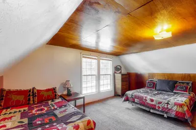 a attic room with a bed and a window at Maul Cabin in Shaver Lake