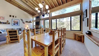 a dining room with a wooden table and some windows at Beautiful 2 BR with 2 Lofts SLOPESIDE! in Mammoth Lakes