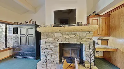 a living room with a stone fireplace with a tv at Spacious Two Bedroom Condo with Loft! in Mammoth Lakes