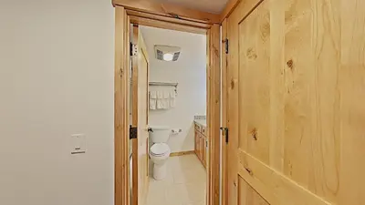 a bathroom with a toilet and a wooden door at Spacious Two Bedroom Condo with Loft! in Mammoth Lakes
