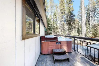 a hot tub on a deck with a chair at Pine Cone Cabin in Soda Springs