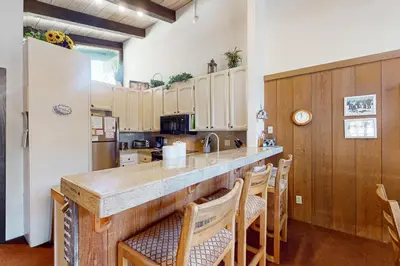 a kitchen with a counter with chairs and a refrigerator at Chateau Sans Nom 29 in Mammoth Lakes