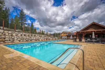 a swimming pool with a stone wall and a building at Comfortable and Convenient Truckee Condo in Truckee