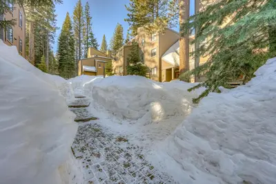 a path covered in snow next to a building at Enjoyable Northstar Condo in Kingswood Estates