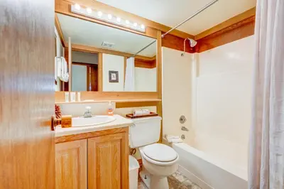 a bathroom with a toilet and a sink and a mirror at Cheery Gold Bend Family Condo in Truckee