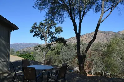 a table and chairs on a patio with mountains in the background at In The Oaks in Three Rivers