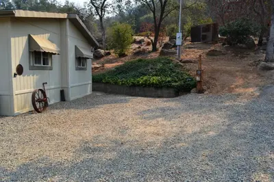 a small house with a wheel next to a gravel driveway at In The Oaks in Three Rivers