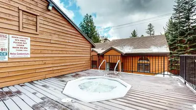 a hot tub on a deck in front of a house at Helios North #6 condo in Mammoth Lakes