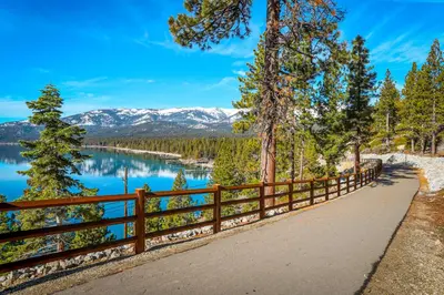 a path next to a lake with mountains in the background at Incline Oasis in Incline Village