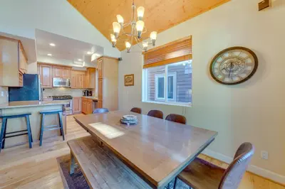 a dining room with a wooden table and a clock on the wall at Central Townhome Less Than 1 Mi to The Village at Mammoth! in Mammoth Lakes